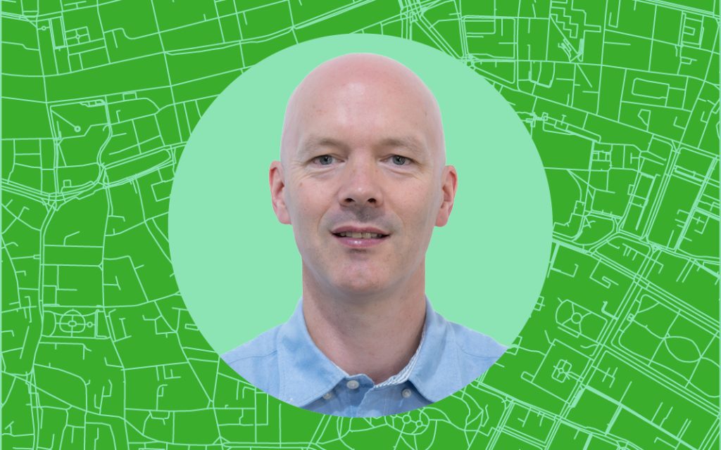 Headshot of person wearing blue shirt superimposed onto a stylised satellite map of Dublin